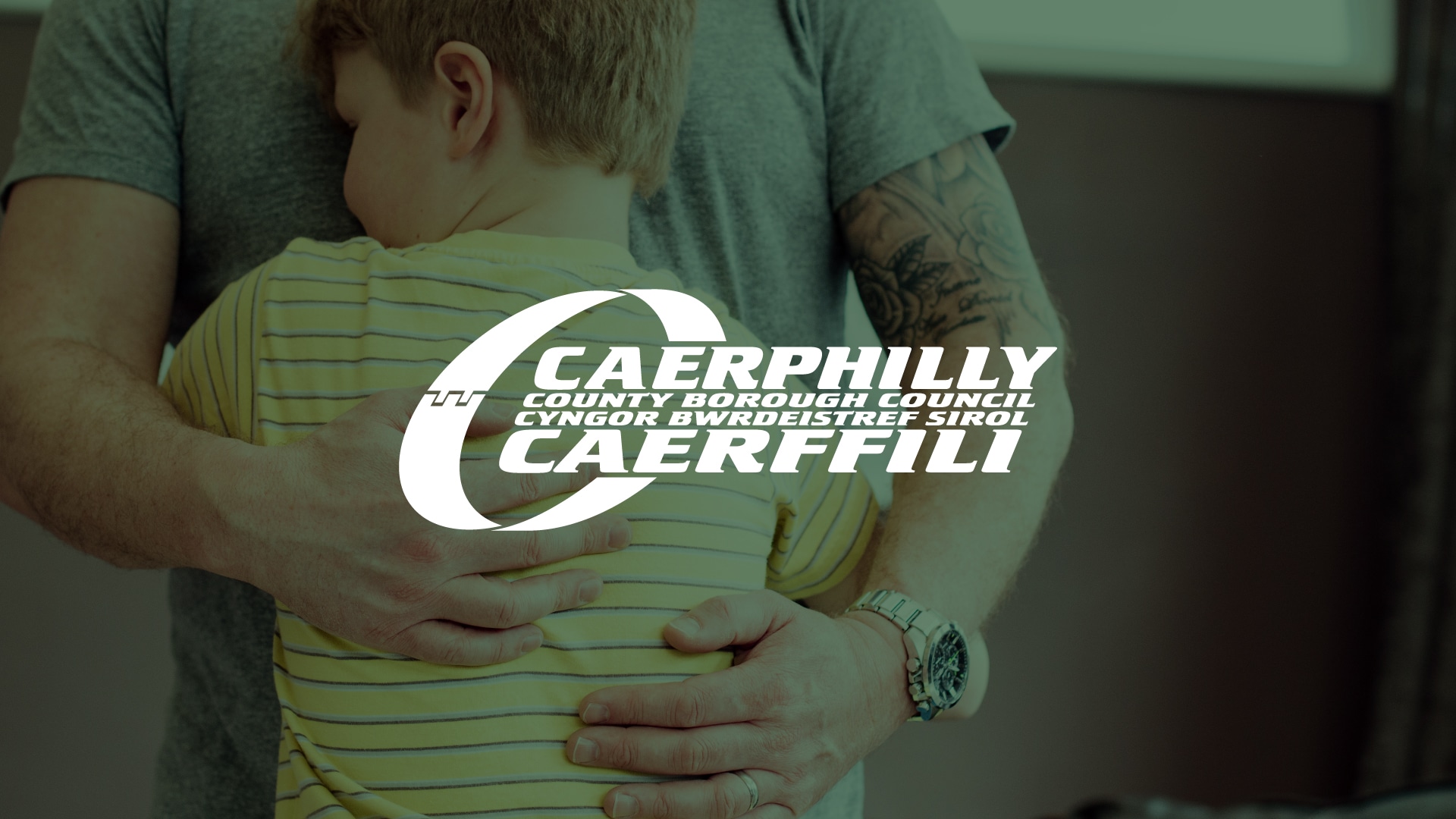 An image of a child embracing an adult overlapped by the Caerphilly Council logo